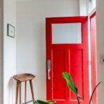 Entrada de una casa con puerta roja y un banco de madera