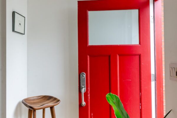 Entrada de una casa con puerta roja y un banco de madera