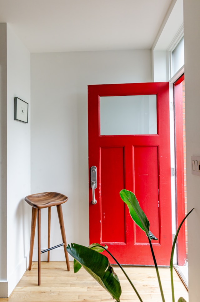 Entrada de una casa con puerta roja y un banco de madera