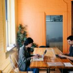 Mujer y hombre trabajando en una laptop dentro de una oficina de coworking