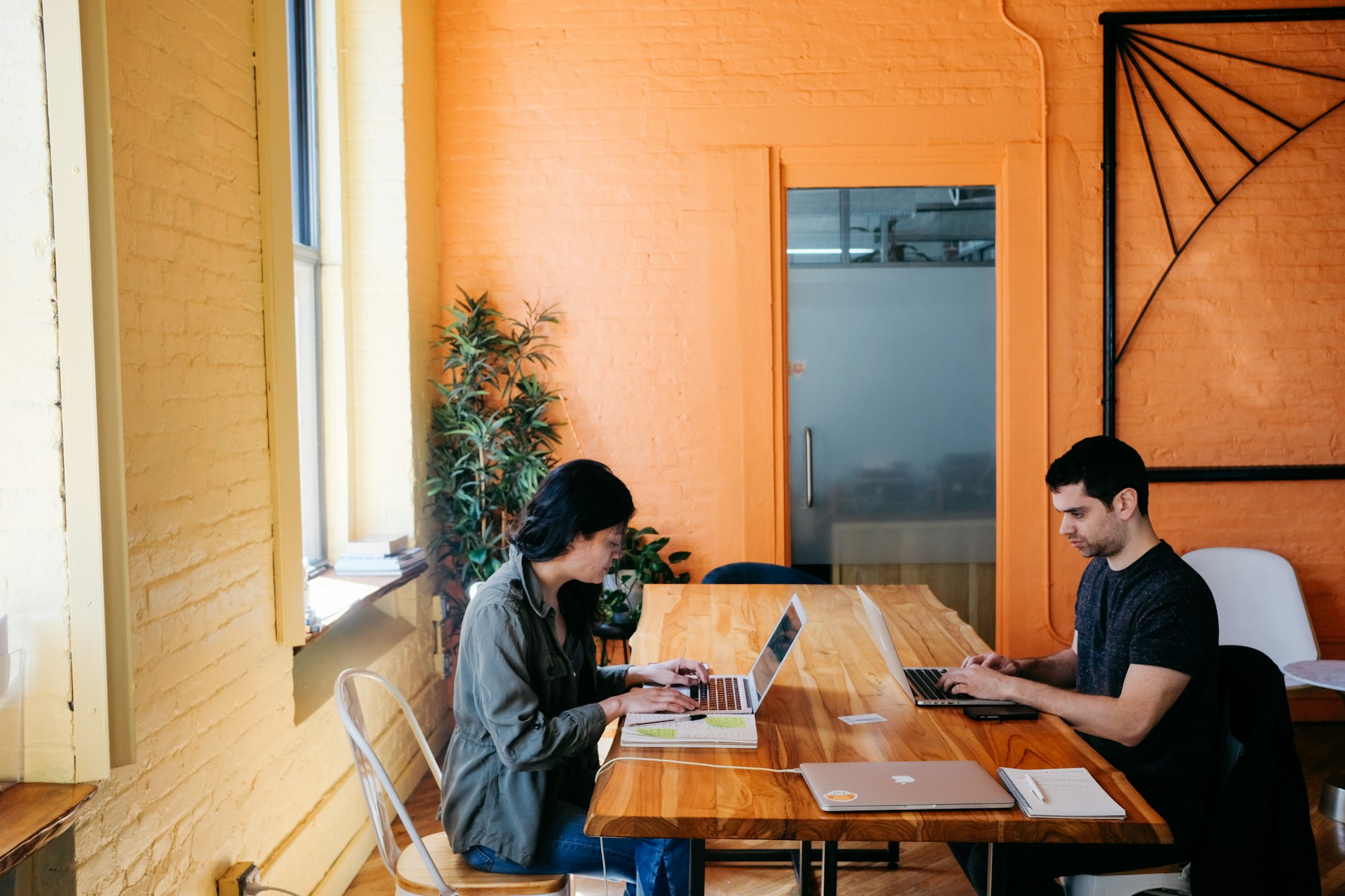 Mujer y hombre trabajando en una laptop dentro de una oficina de coworking