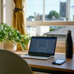 Escritorio con computadora y ventana a un lado.