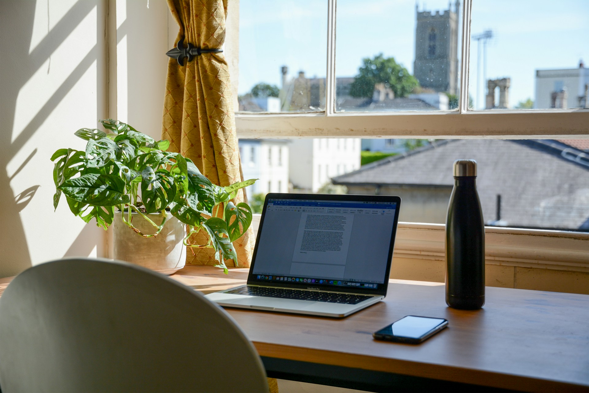 Escritorio con computadora y ventana a un lado.