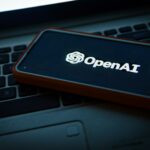 Telefono sobre una laptop con la imagen de Open AI