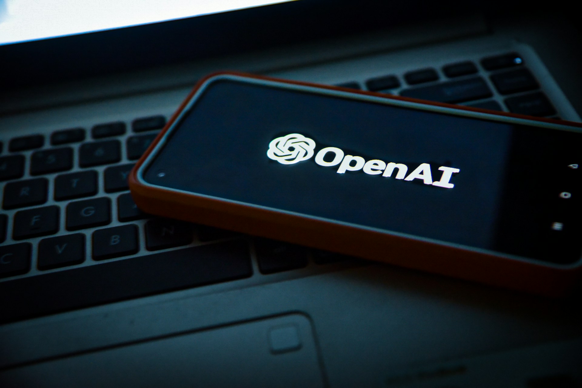 Telefono sobre una laptop con la imagen de Open AI