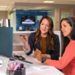 Dos mujeres frente a una computadora trabajando.